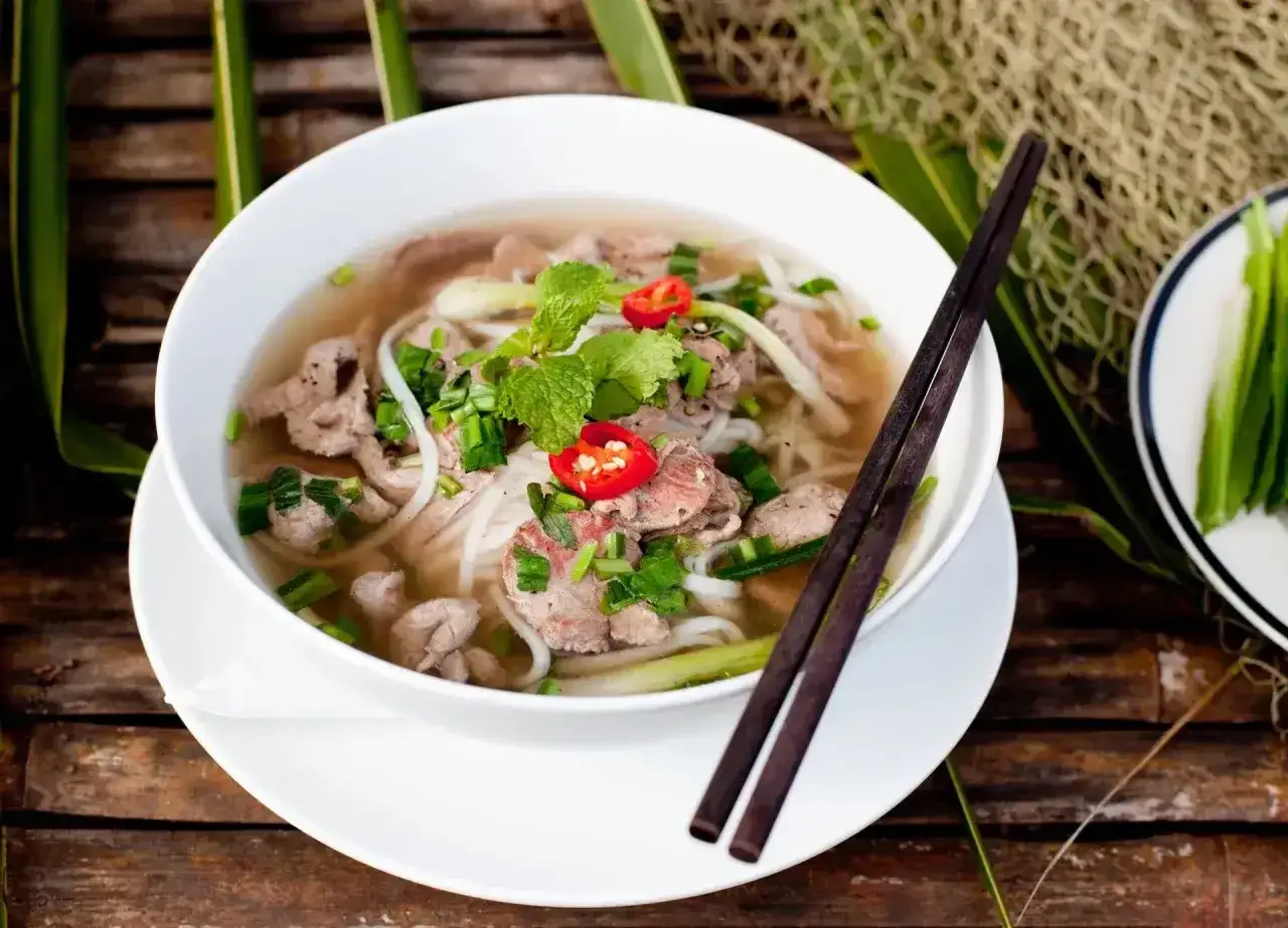 Aromaticzne pho z wołowiną, makaronem ryżowym, świeżą miętą i chili. Pałeczki czekają, by zanurzyć się w tym pysznym daniu.