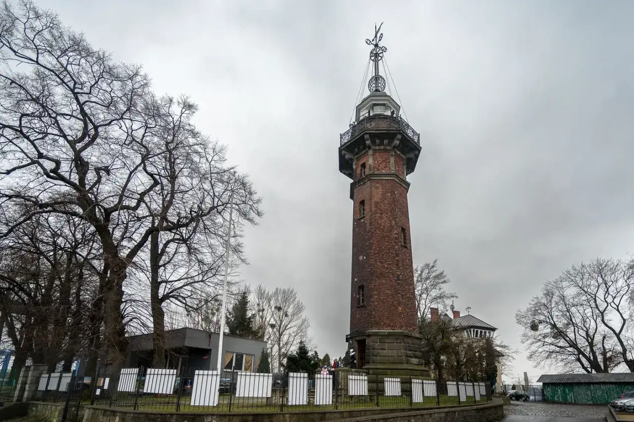 Wysoka, ceglana wieża nawigacyjna g&oacute;ruje nad terenem, przypominając o historii i przyszłości nowego portu gdańsk.