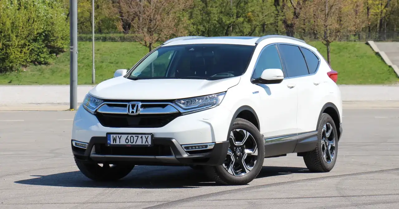Biała Honda CRV 2025 z eleganckimi felgami stoi na tle zieleni.
