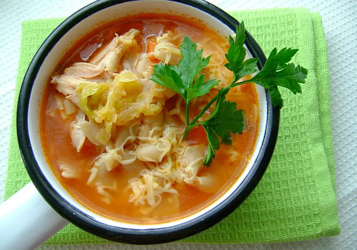 A miseczka parującej zupy minestrone z kurczakiem, fasolą i makaronem, ozdobiona gałązką natki pietruszki.