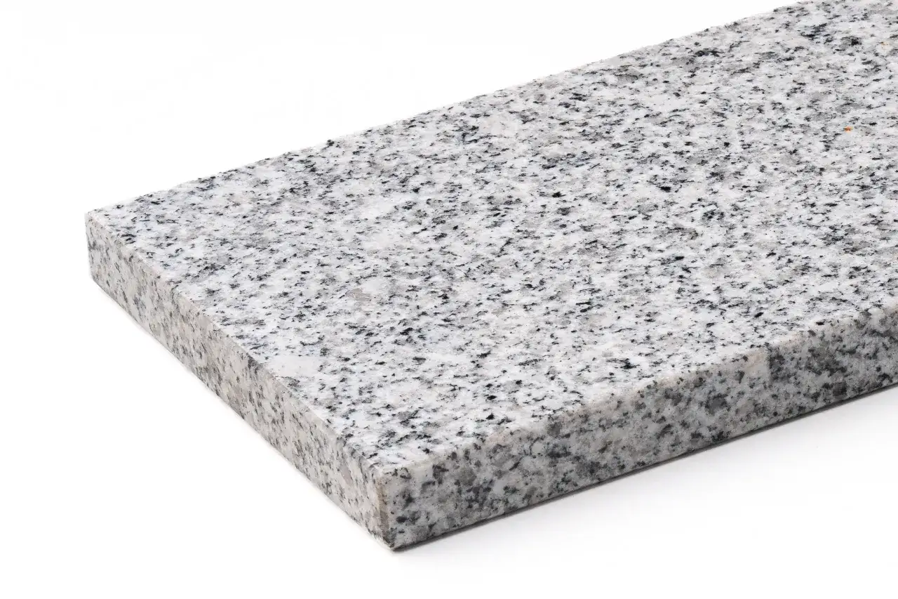 Fragment blatu z bianco perla granit, o jasnej, nakrapianej powierzchni z czarnymi i szarymi kryształkami.
