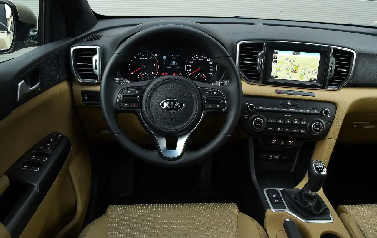 Wnętrze Kia Sportage IV z nawigacją GPS na ekranie, kierownicą i panelem sterowania.
