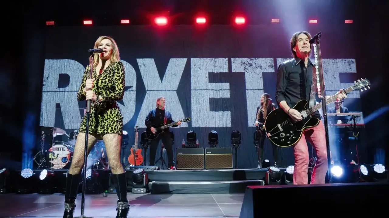 Roxette na żywo, wykonując swoje największe przeboje. Wokalistka w panterkowej sukience i gitarzysta w czarnej koszuli.