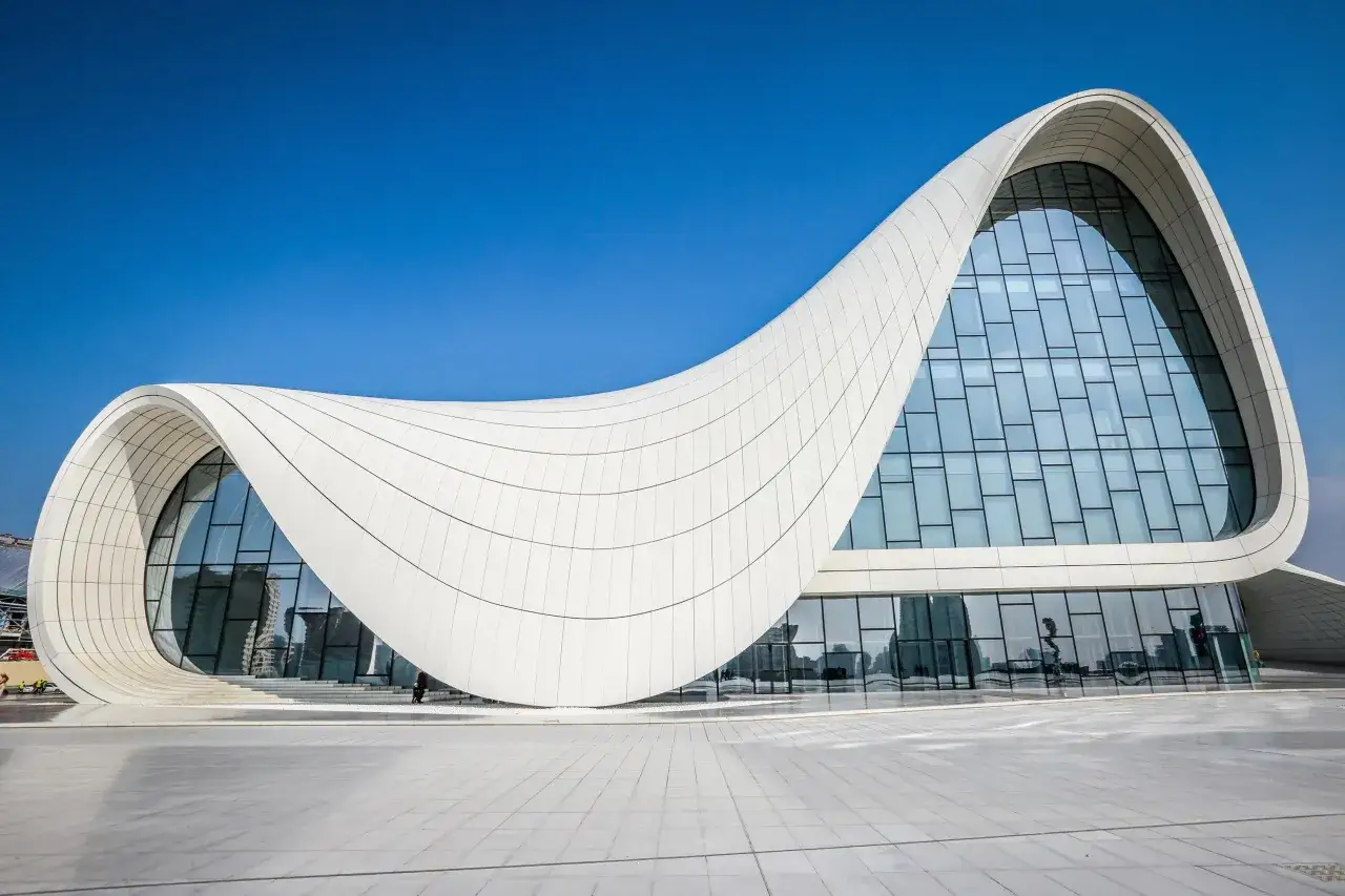 Futurystyczny budynek Centrum Heydara Alijewa, dzieło Zaha Hadid, faluje pod błękitnym niebem.