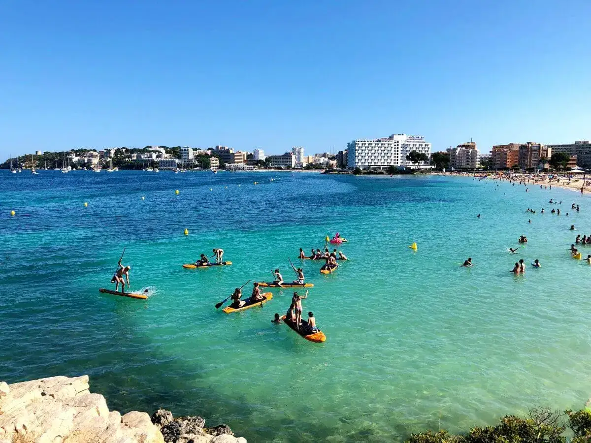 Disfrutando de un día soleado en Mallorca con niños, practicando paddle surf en aguas cristalinas.