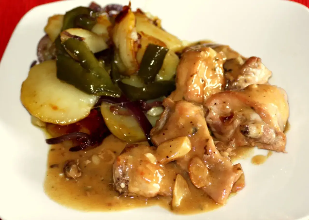 Delicioso plato de conejo al ajillo con patatas, pimientos y cebolla.
