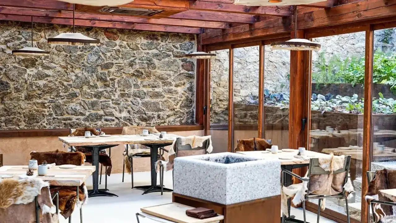 Mesas rústicas con pieles y vistas al jardín, ideal para comer en la sierra de Madrid.