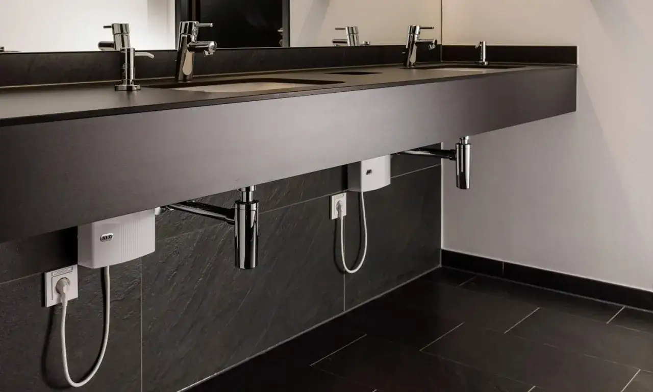 Moderne Waschbecken mit verdeckten AEG Durchlauferhitzer 24 kW. Elegantes Design f&uuml;r Ihr Bad.