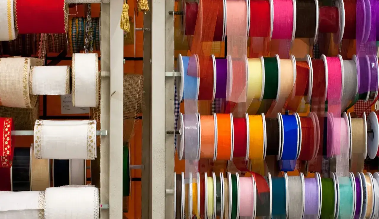 Estanter&iacute;as llenas de rollos de tela para lazos de colores vibrantes y texturas variadas, perfectos para cualquier proyecto creativo.