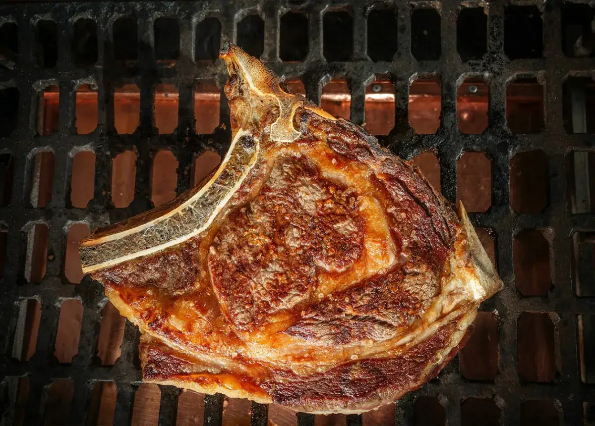 Un jugoso chuletón se cocina a la perfección en la parrilla, listo para hacer una barbacoa inolvidable.