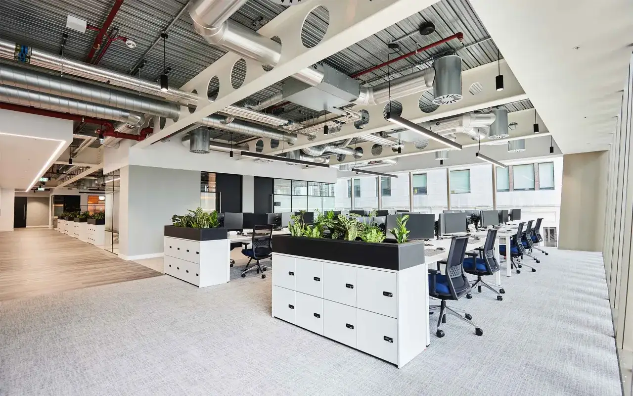 Bureau moderne, organisation open space avec bureaux, plantes et rangements.