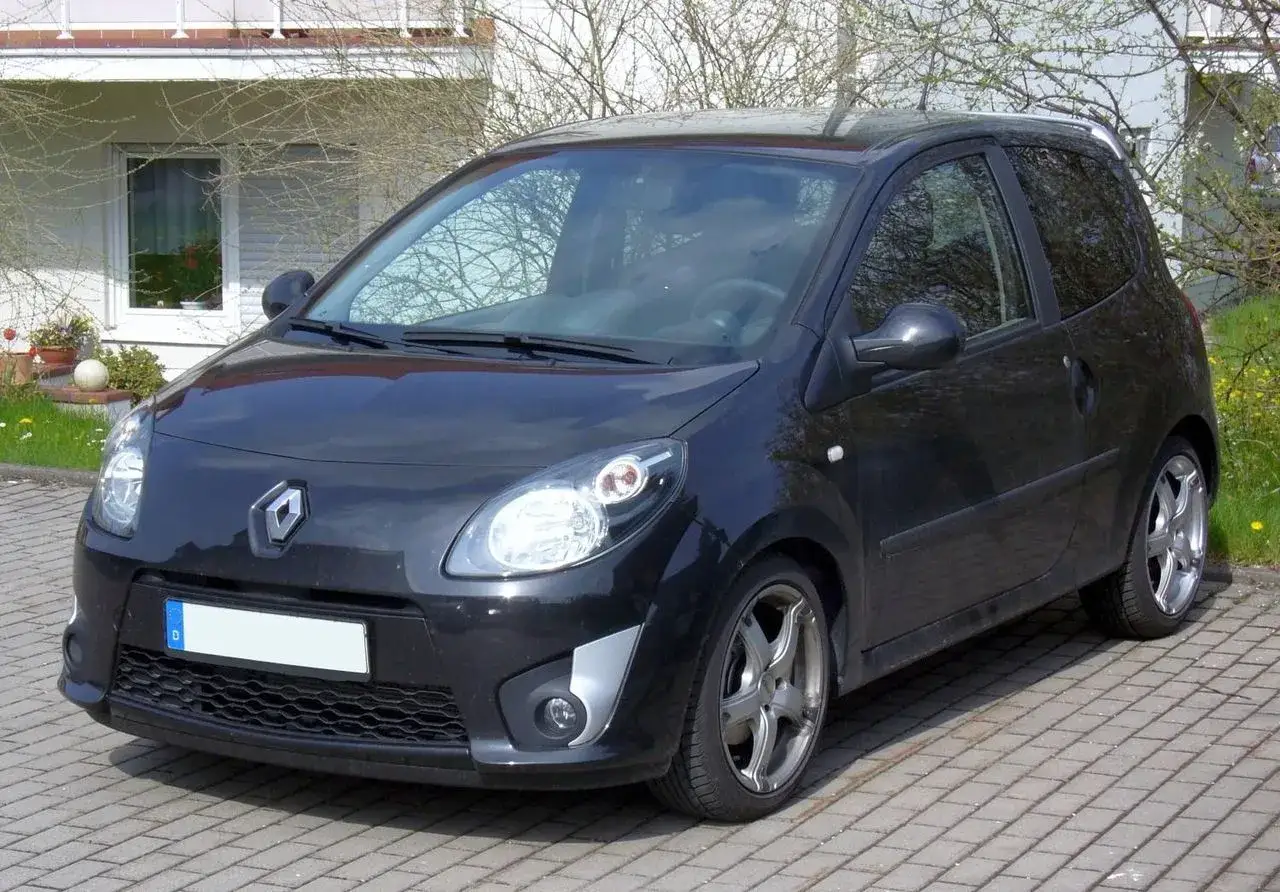 Renault Twingo 2 noire gar&eacute;e sur pav&eacute;s. Les jantes alliage sugg&egrave;rent une recherche de performance, peut-&ecirc;tre li&eacute;e &agrave; la dimension pneu Twingo 2.