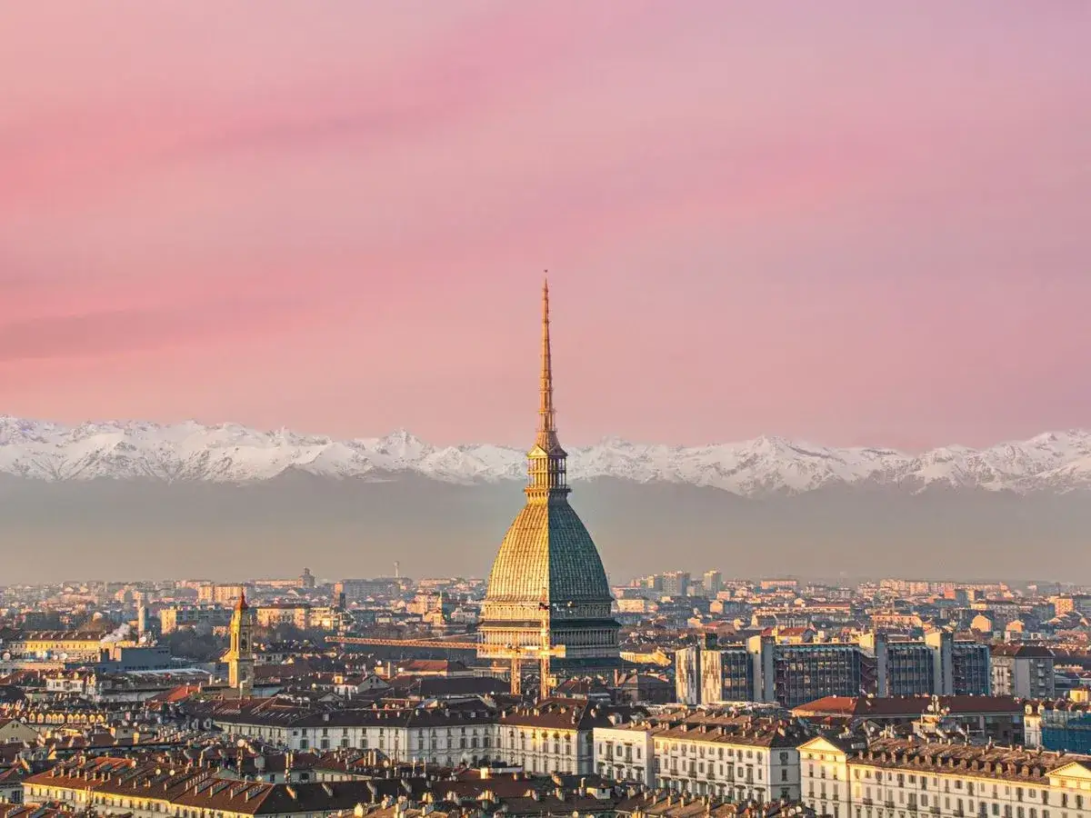 Molto bello, en solnedg&aring;ng &ouml;ver Turin, Italien, med sn&ouml;kl&auml;dda berg i bakgrunden.