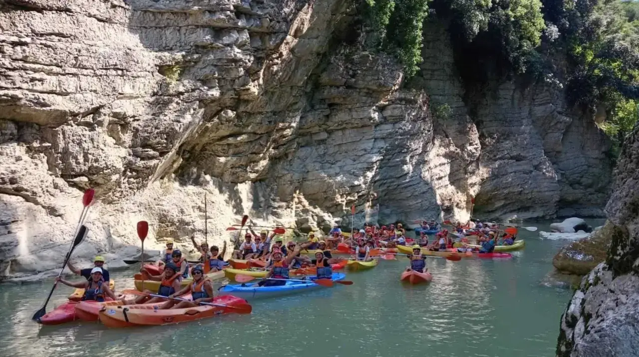 Gruppo di canoa esplora un canyon con pareti rocciose imponenti, navigando tra le marmitte dei giganti scavate dall'acqua.