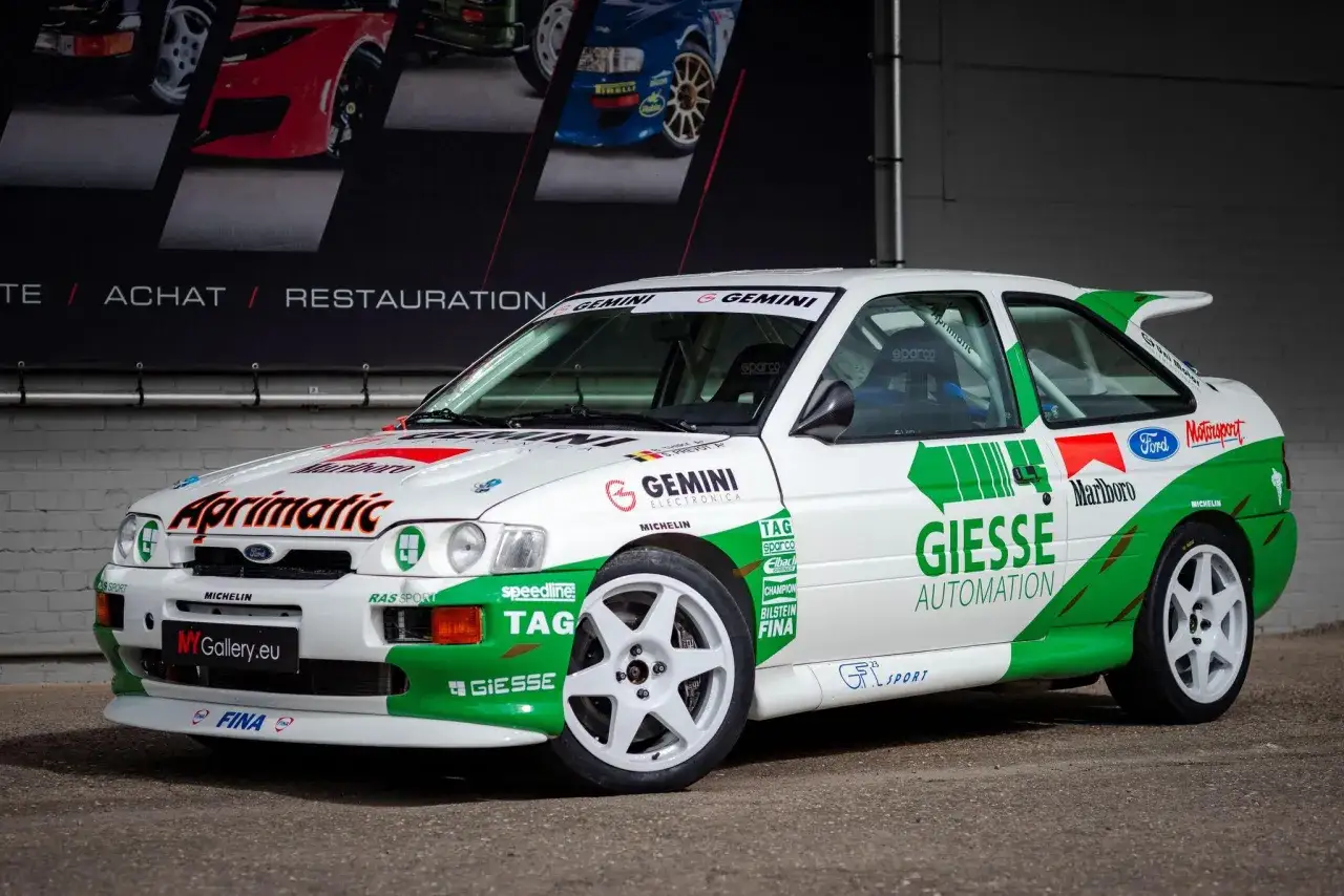 Biały Ford Escort Cosworth z zielonymi i czerwonymi akcentami, gotowy do rajdu.