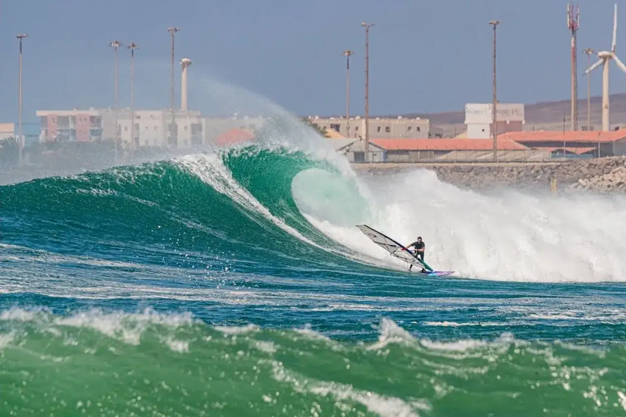 Wyspy Zielonego Przylądka w styczniu: wiatr i fale idealne do windsurfingu. W tle zabudowania i wiatraki.