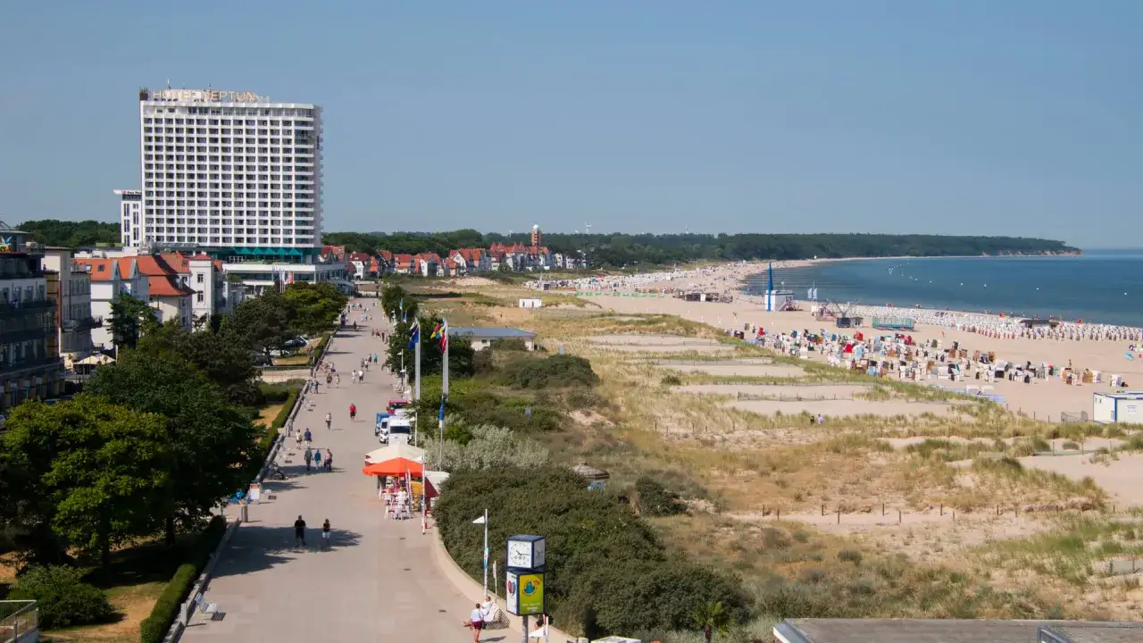 Ein sonniger Tag am Strand von Warnemünde, wo man viel unternehmen kann: Spaziergänge auf der Promenade, Entspannung am Meer und das Hotel Neptun.