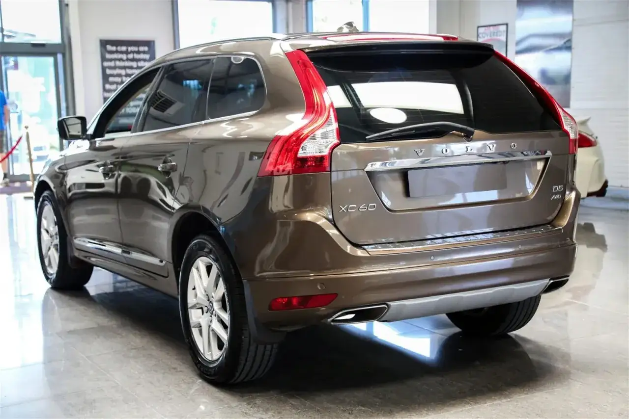 Brązowe Volvo XC60 z zamontowanymi chlapaczami, gotowe na każdą drogę.