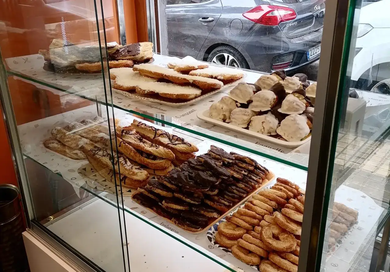 Dulces variados en escaparate: napolitanas de chocolate, bizcochos con coco y glaseados. ¡La mejor pastelería Zaragoza!