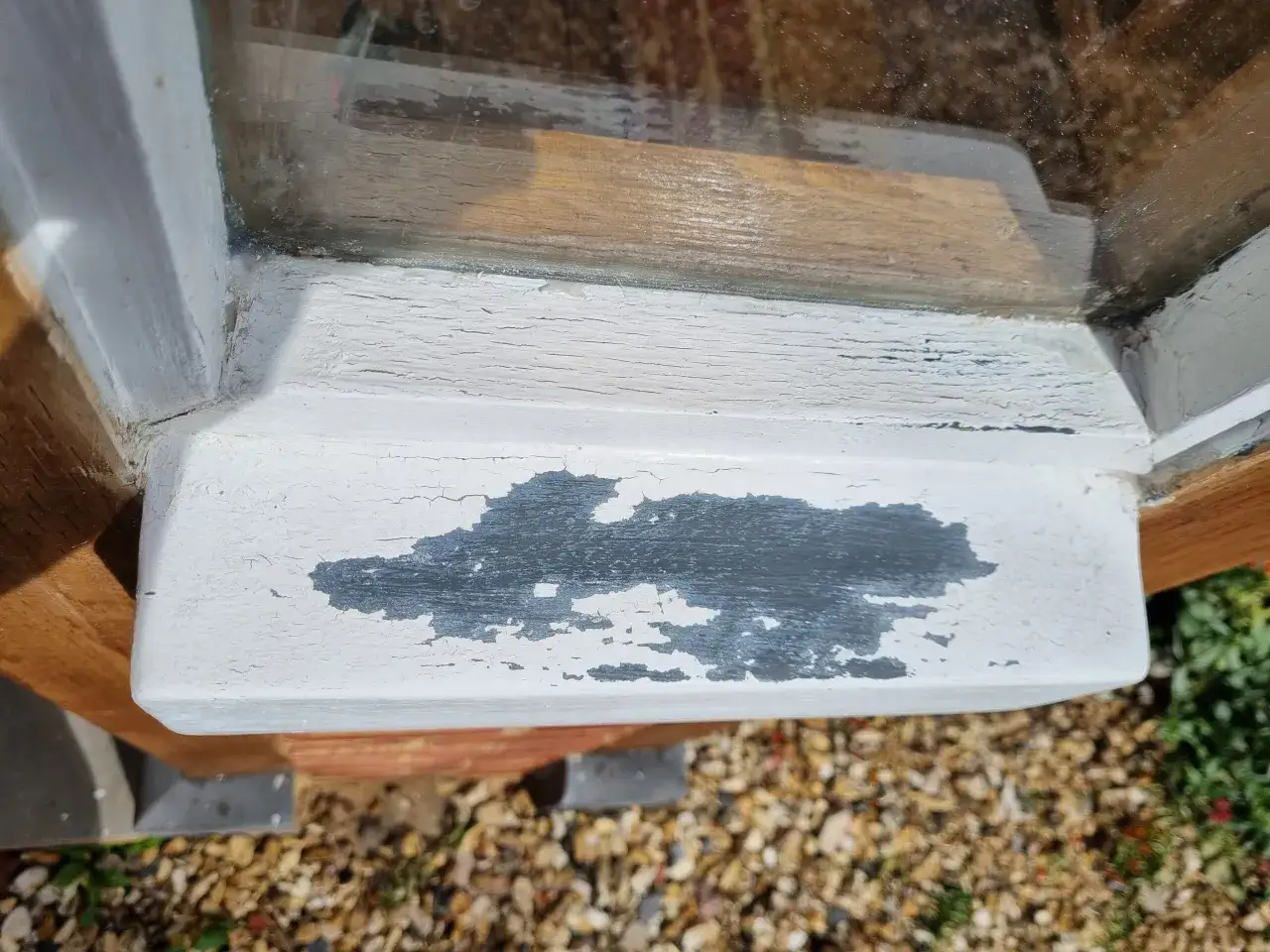 La peinture s'&eacute;caille sur le rebord d'une fen&ecirc;tre en bois, r&eacute;v&eacute;lant le bois brut. Il faut peindre cette fen&ecirc;tre bois d&eacute;j&agrave; peinte.