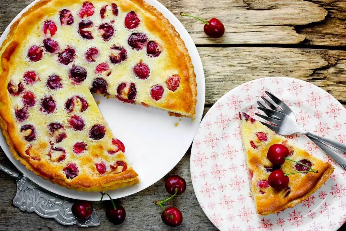 Delizioso clafoutis di ciliegie, con una fetta servita su un piatto decorato.