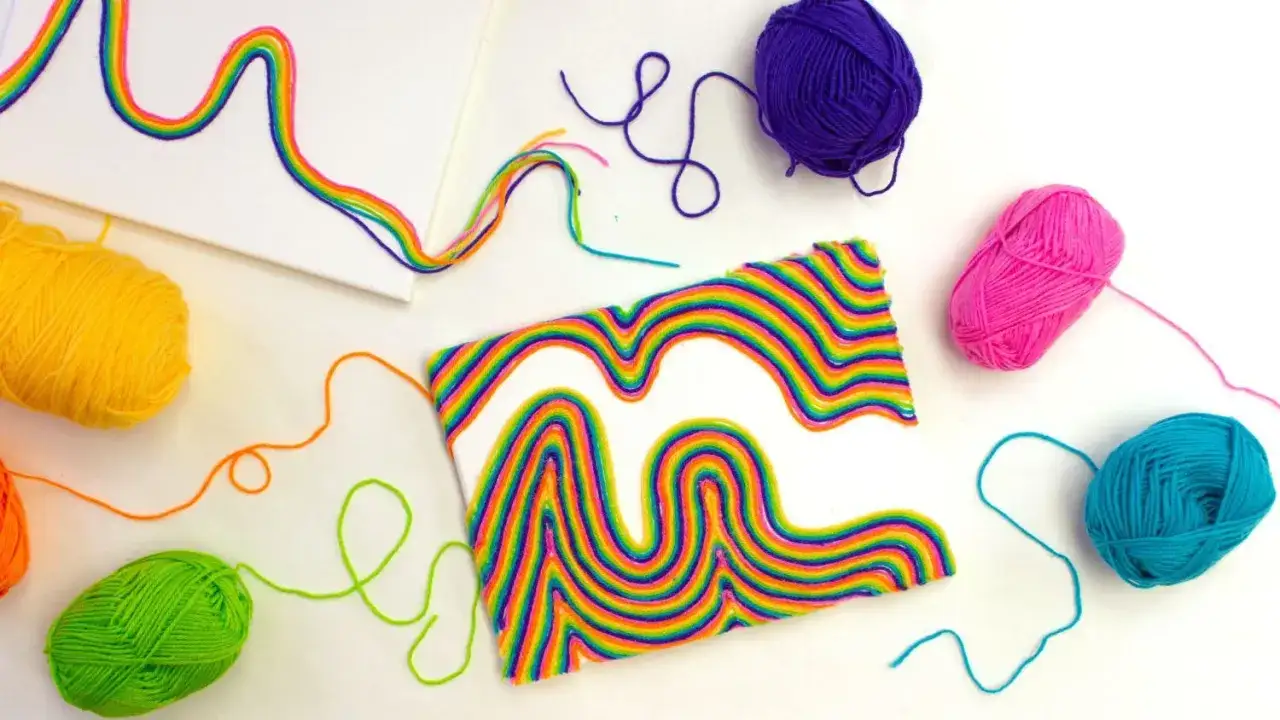 Kolorowe sznurki tworzą tęczowe wzory na pł&oacute;tnie. To świetne **string art dla dzieci**, kt&oacute;re rozwijają kreatywność.