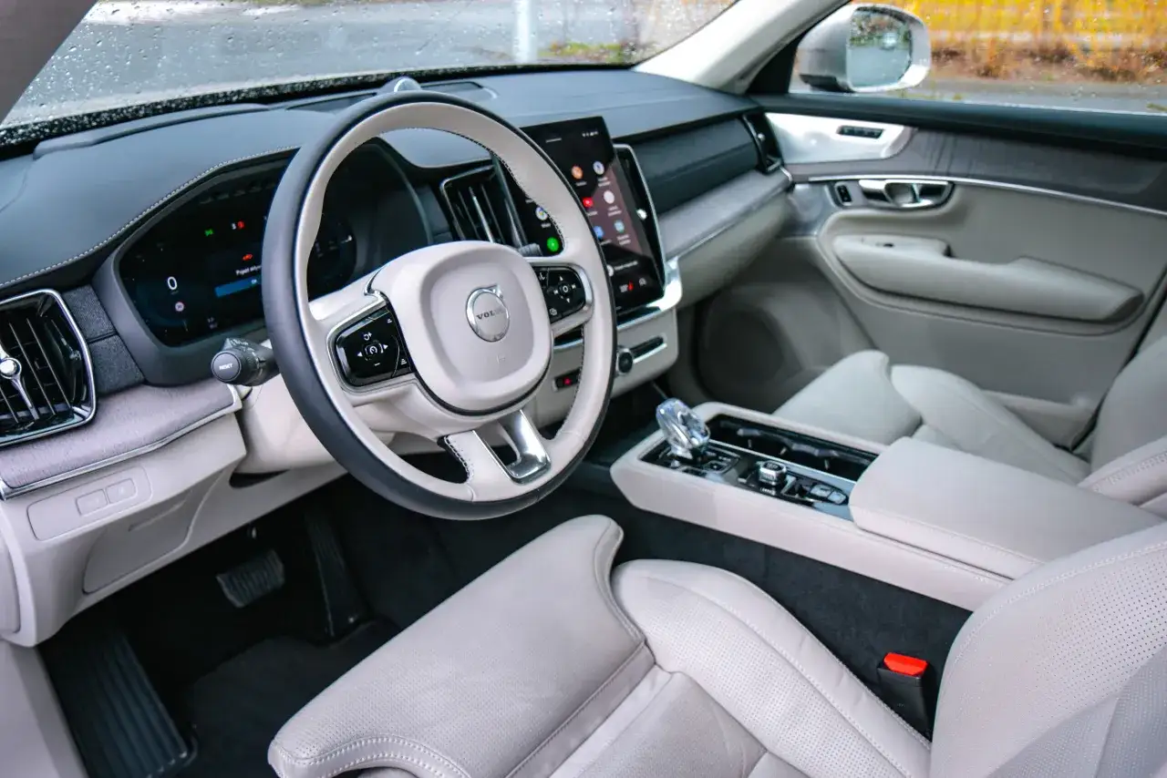 Wnętrze luksusowego Volvo XC90 T8 z jasną tapicerką, nowoczesnym panelem i ekranem dotykowym.