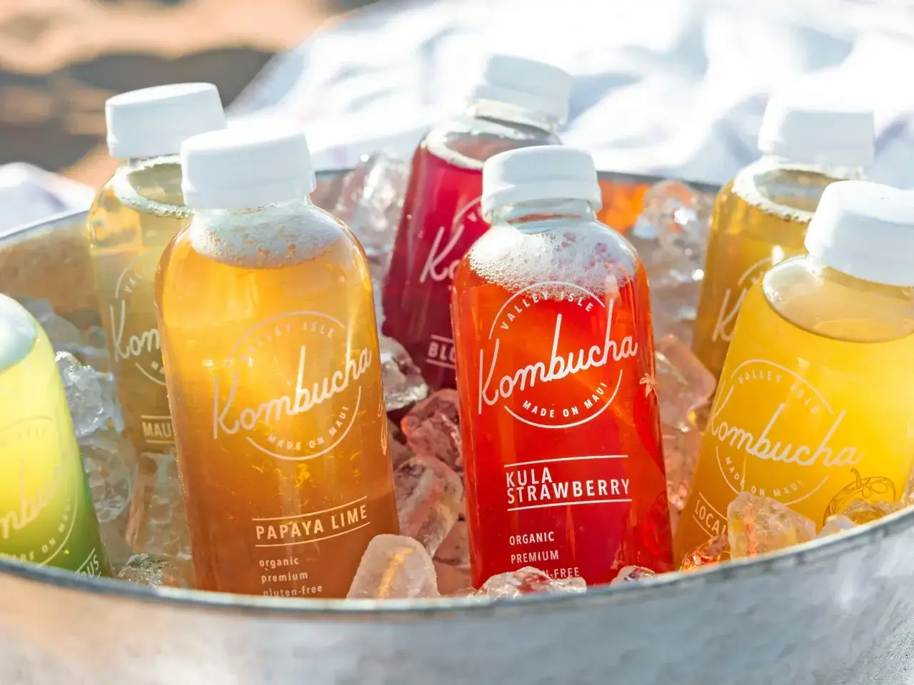 Plusieurs bouteilles de kombucha, un d&eacute;licieux sucre ferment&eacute; aux saveurs fruit&eacute;es, reposent sur de la glace.