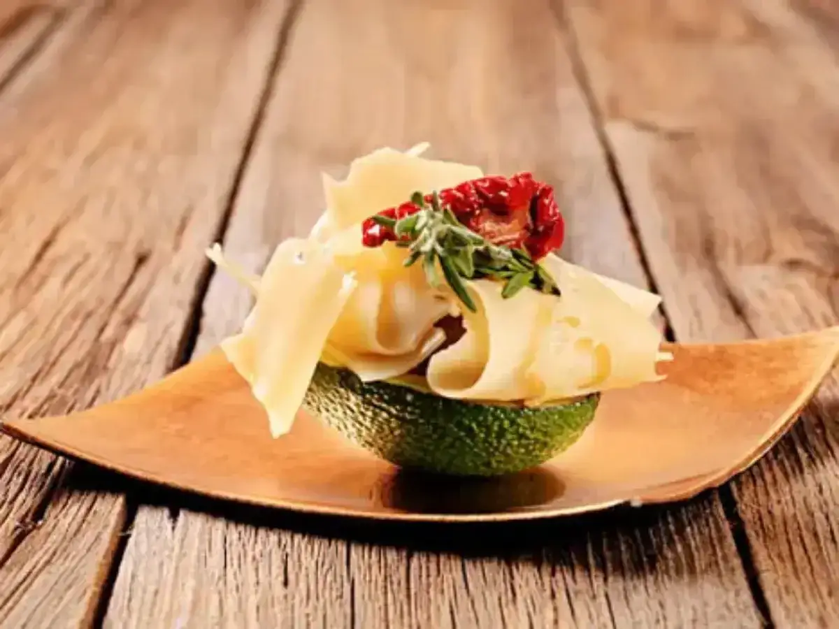 Awokado z serem i suszonym pomidorem na talerzyku – idealne keto przekąski.