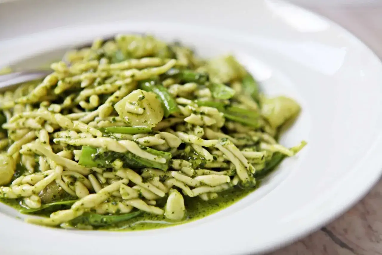 Un piatto di trofie condite con un pesto vibrante, un classico della pasta alla genovese, con fagiolini e patate.