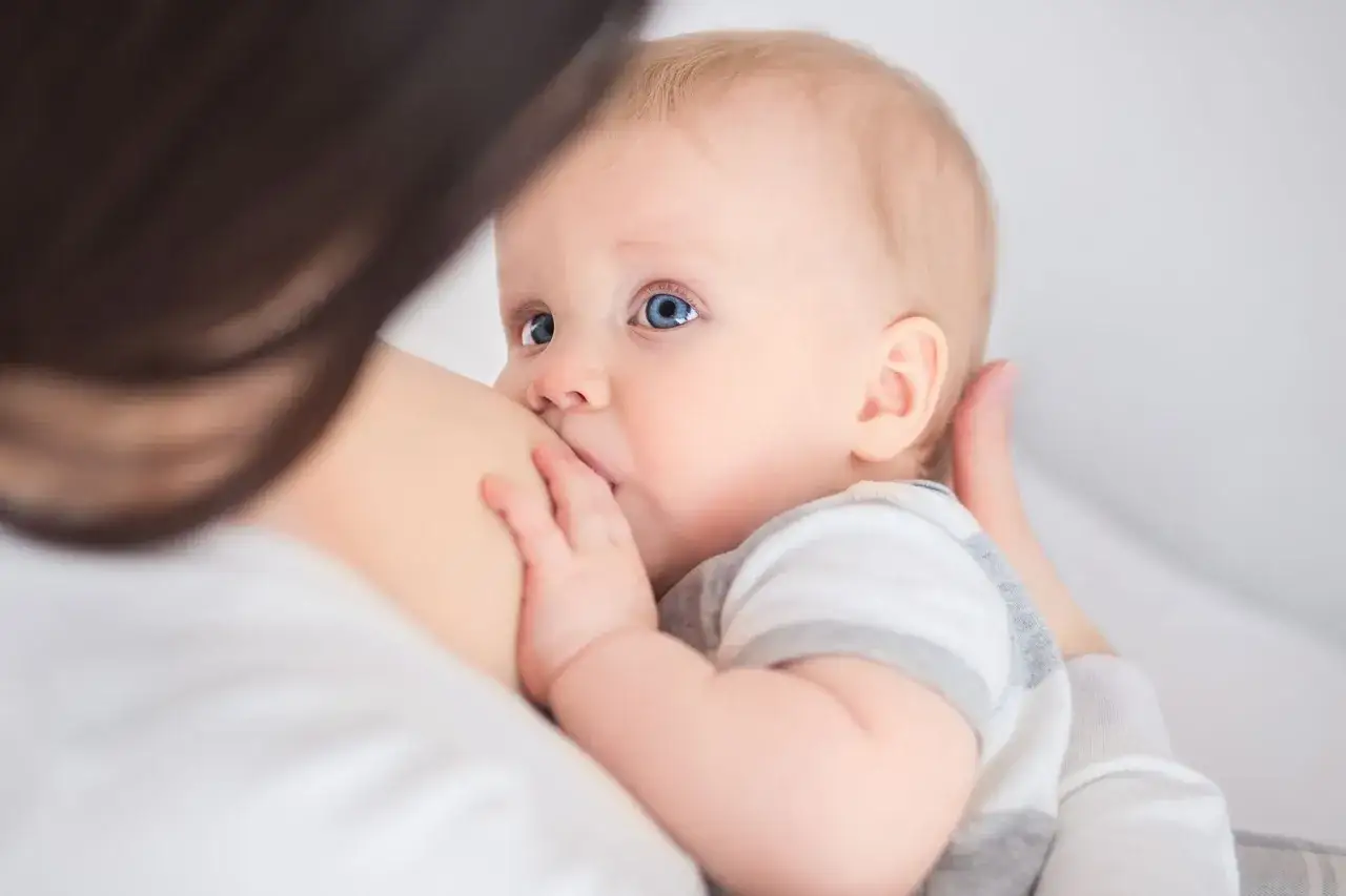 Niemowlę karmione piersią. Mama pije herbatę z szałwii, by złagodzić ból gardła, co może mieć wpływ na dziecko.