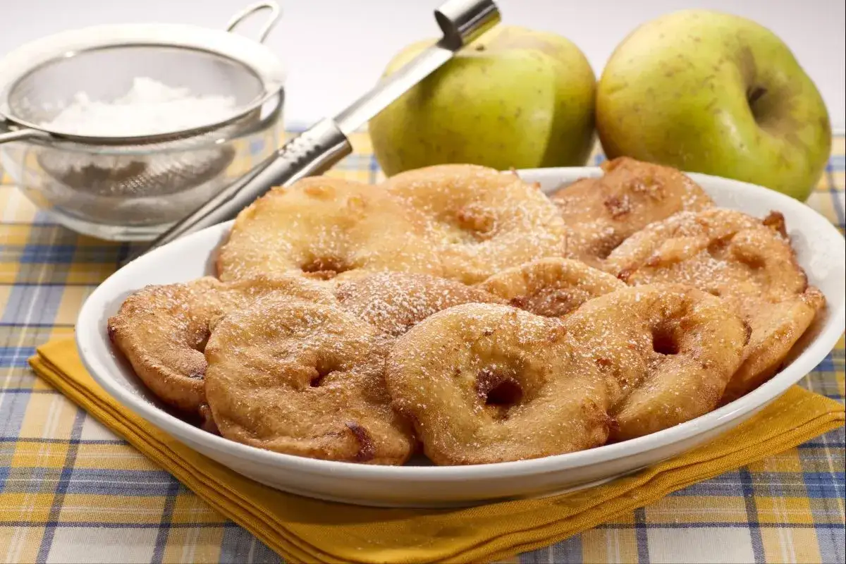 Frittelle di mele dorate, spolverate di zucchero a velo, un dolce che sa di frittelle di una volta.