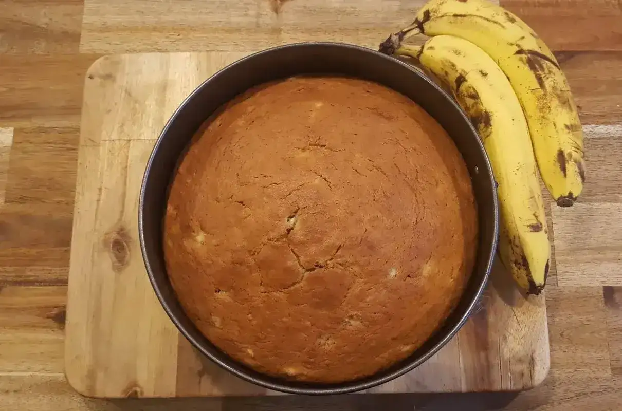 Idealne ciasto bananowe, które zawsze się udaje, właśnie wyjęte z piekarnika. Obok leżą dojrzałe banany.