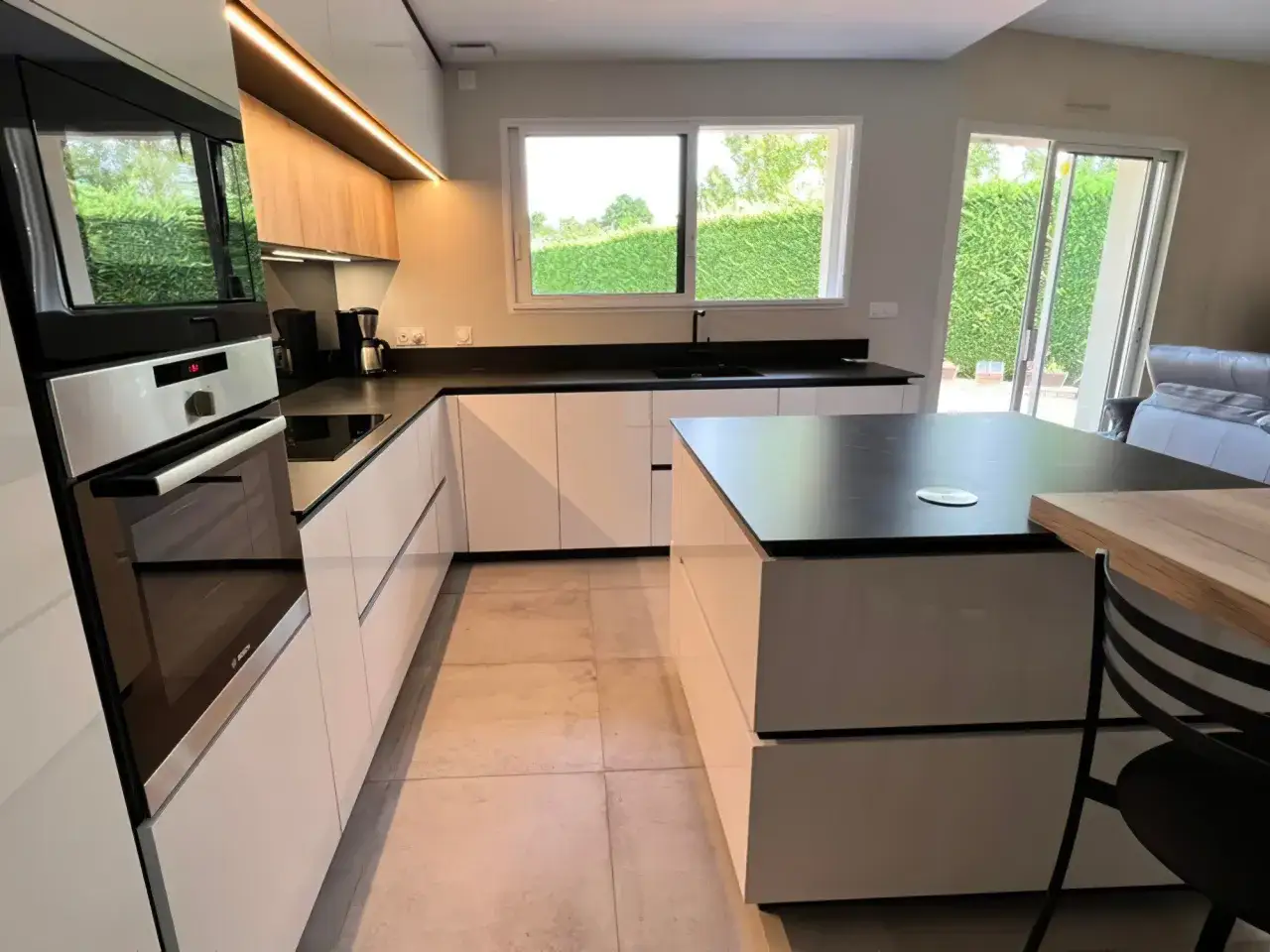 Cuisine blanche moderne avec plan de travail noir. Quelle couleur de plan de travail pour une cuisine blanche ? Le noir offre un contraste saisissant.