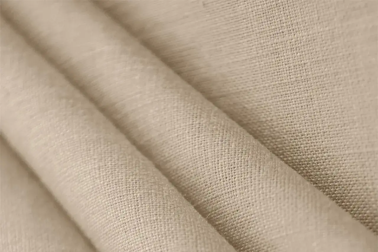 Tessuto in lino naturale, con pieghe morbide che ne esaltano la trama. Un materiale traspirante e resistente.