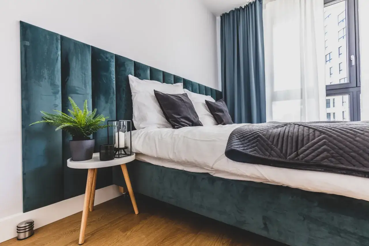 T&ecirc;te de lit capitonn&eacute;e vert &eacute;meraude, quelle hauteur pour une t&ecirc;te de lit ? Un lit douillet avec coussins sombres et plaid gris.