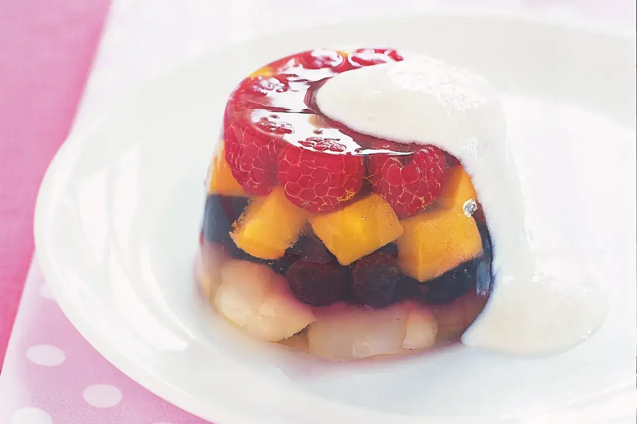Kolorowa galaretka z owocami i bitą śmietaną. Niska galaretka kcal z malinami, borówkami i kawałkami mango.