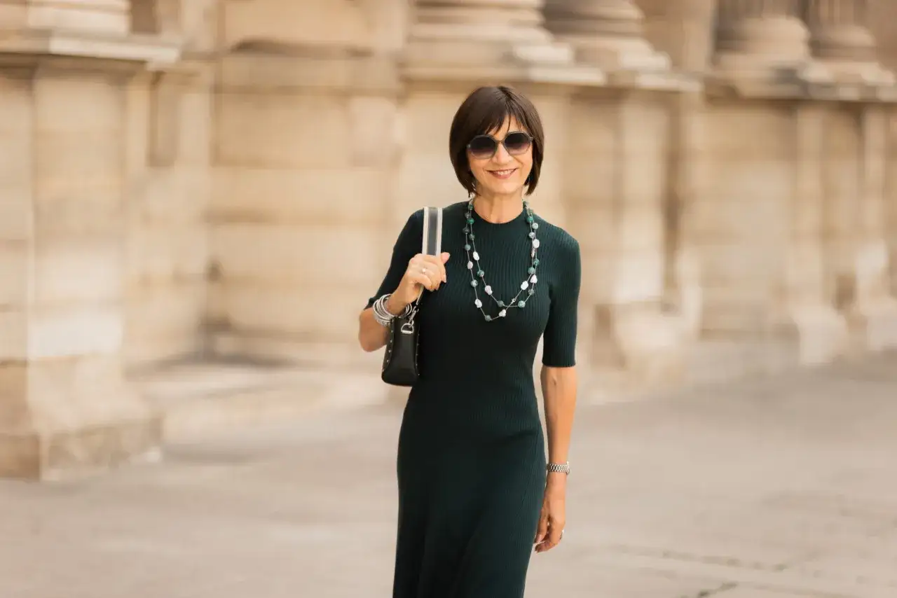 Une femme &eacute;l&eacute;gante en robe verte, collier perl&eacute;, parfaite pour savoir comment s'habiller pour un vernissage.