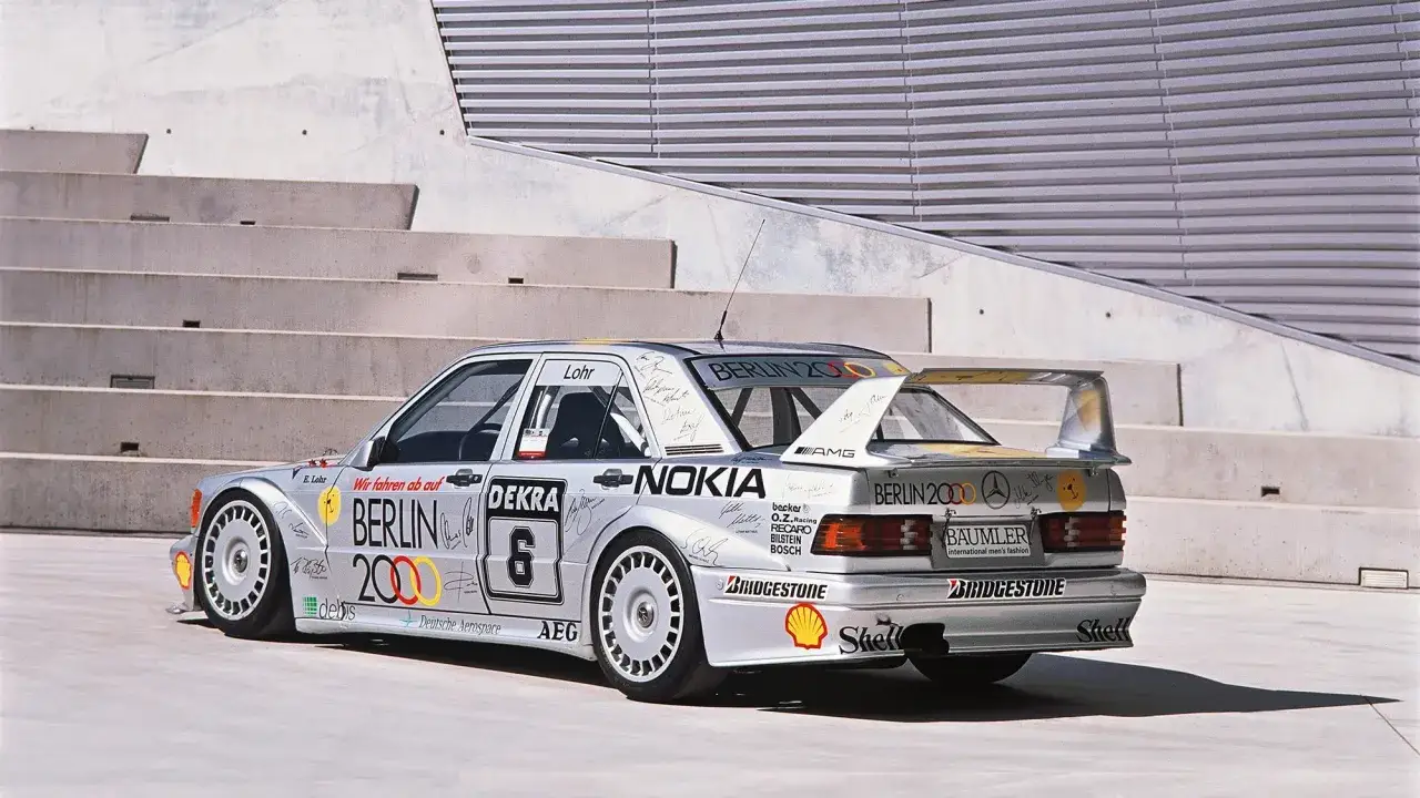 Srebrny Mercedes 190 Evo z licznymi sponsorami i autografami, gotowy do wyścigu.