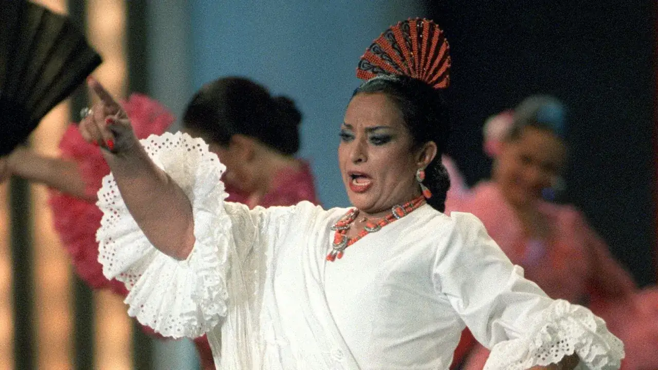 Lola Flores, con su traje blanco y mantón, baila con pasión. ¡Feliz año Lola Flores!
