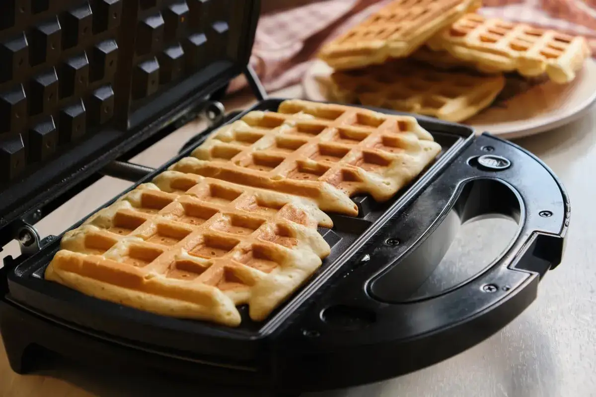 Frisch gebackene Waffeln im Waffeleisen, bereit für den Thermomix-Teig.