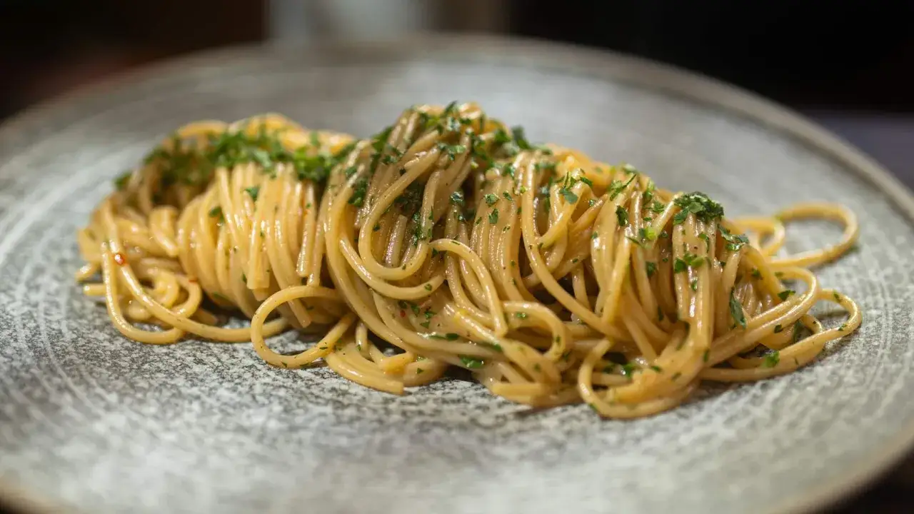 Spaghetti mit Sardellen, Knoblauch und Petersilie auf einem grauen Teller.