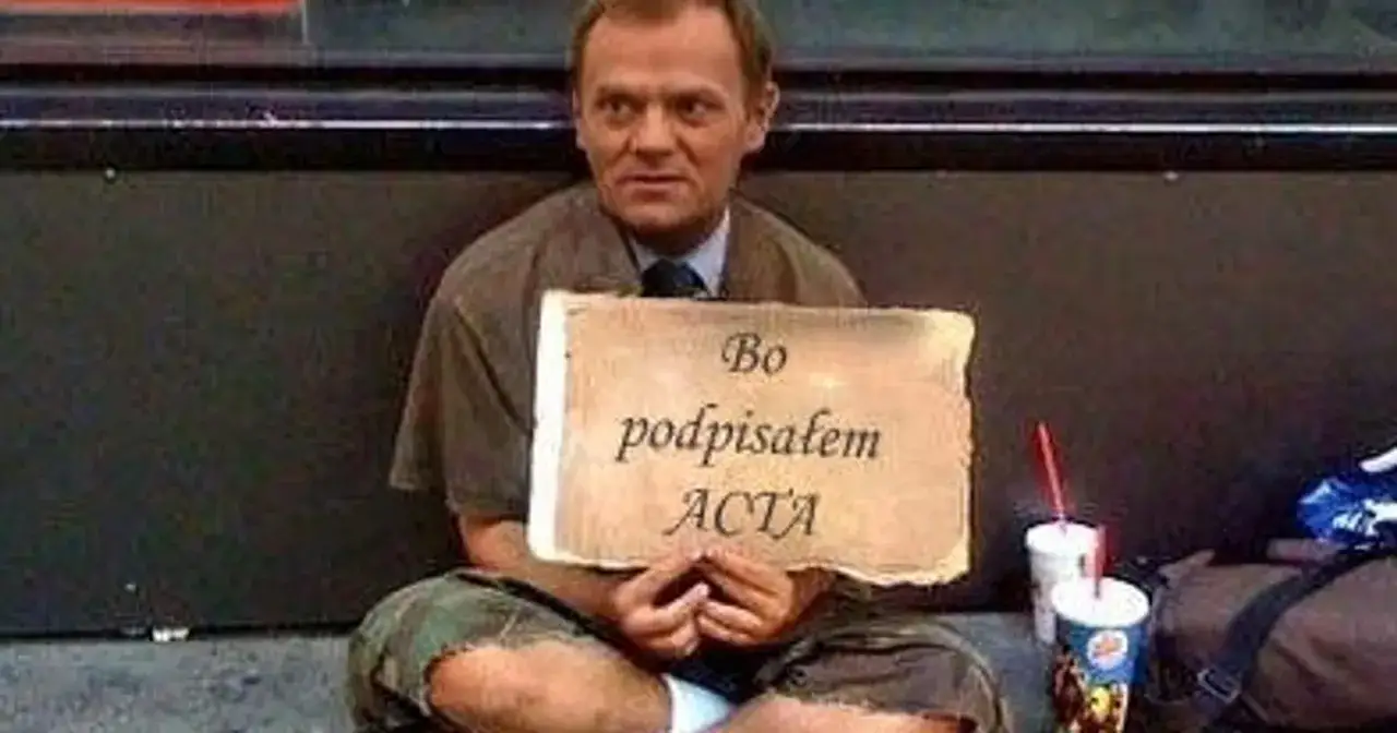 Tusk zdrajca memy: siedzi na ziemi z tabliczką 
