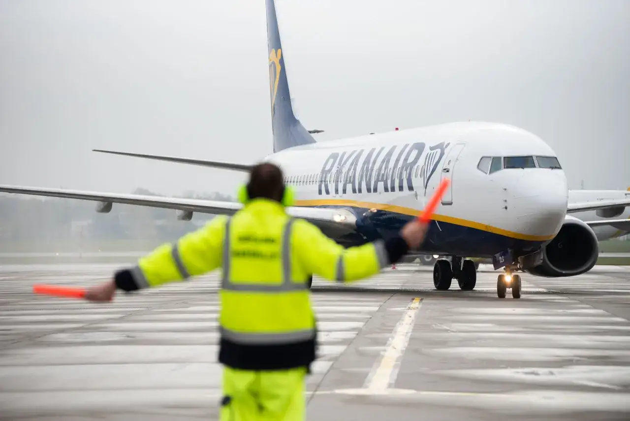 Pracownik lotniska kieruje samolot Ryanair z Łodzi do Alicante.