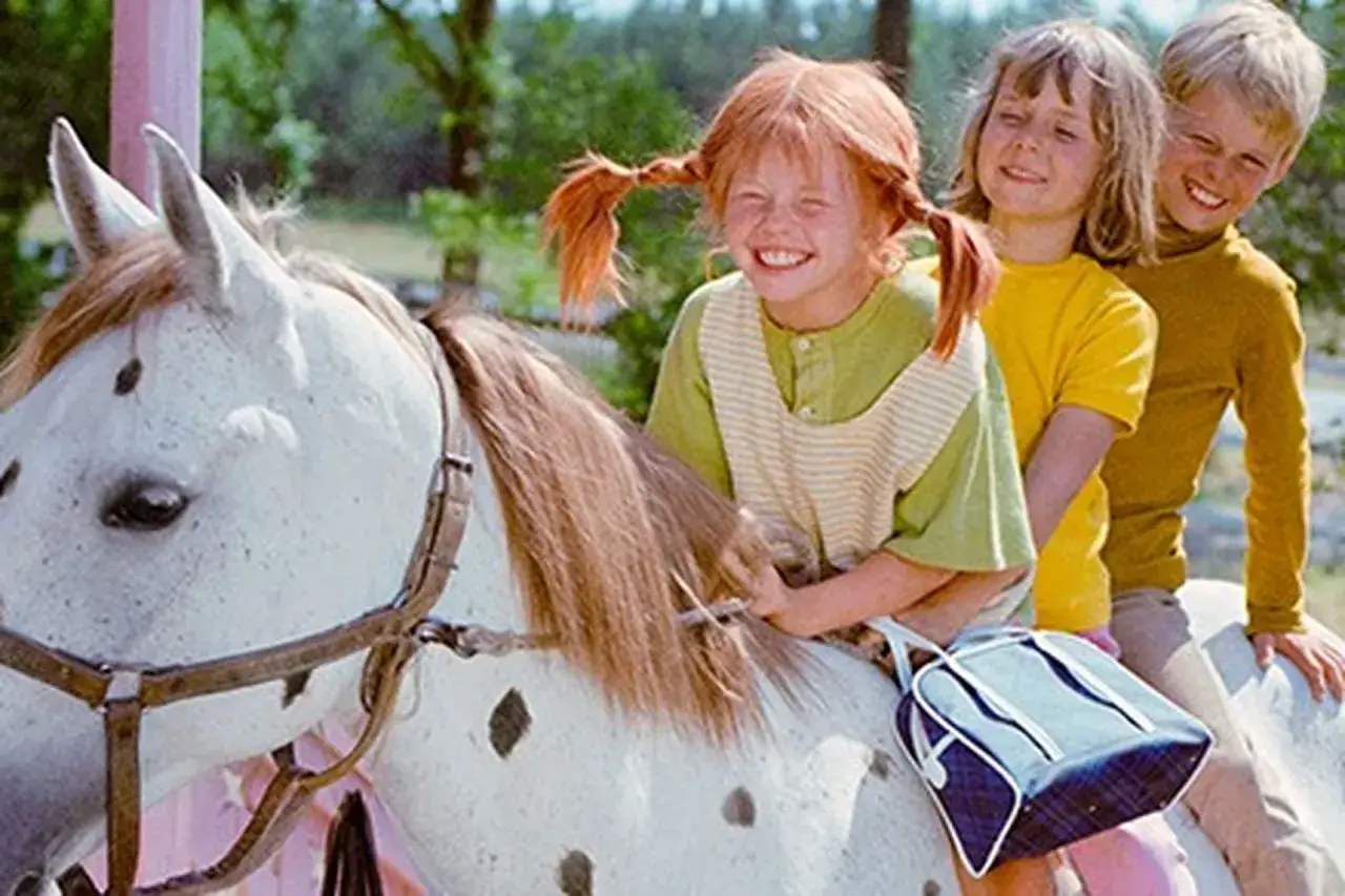 Glada barn, inklusive Annika Pippi, rider på en prickig häst.