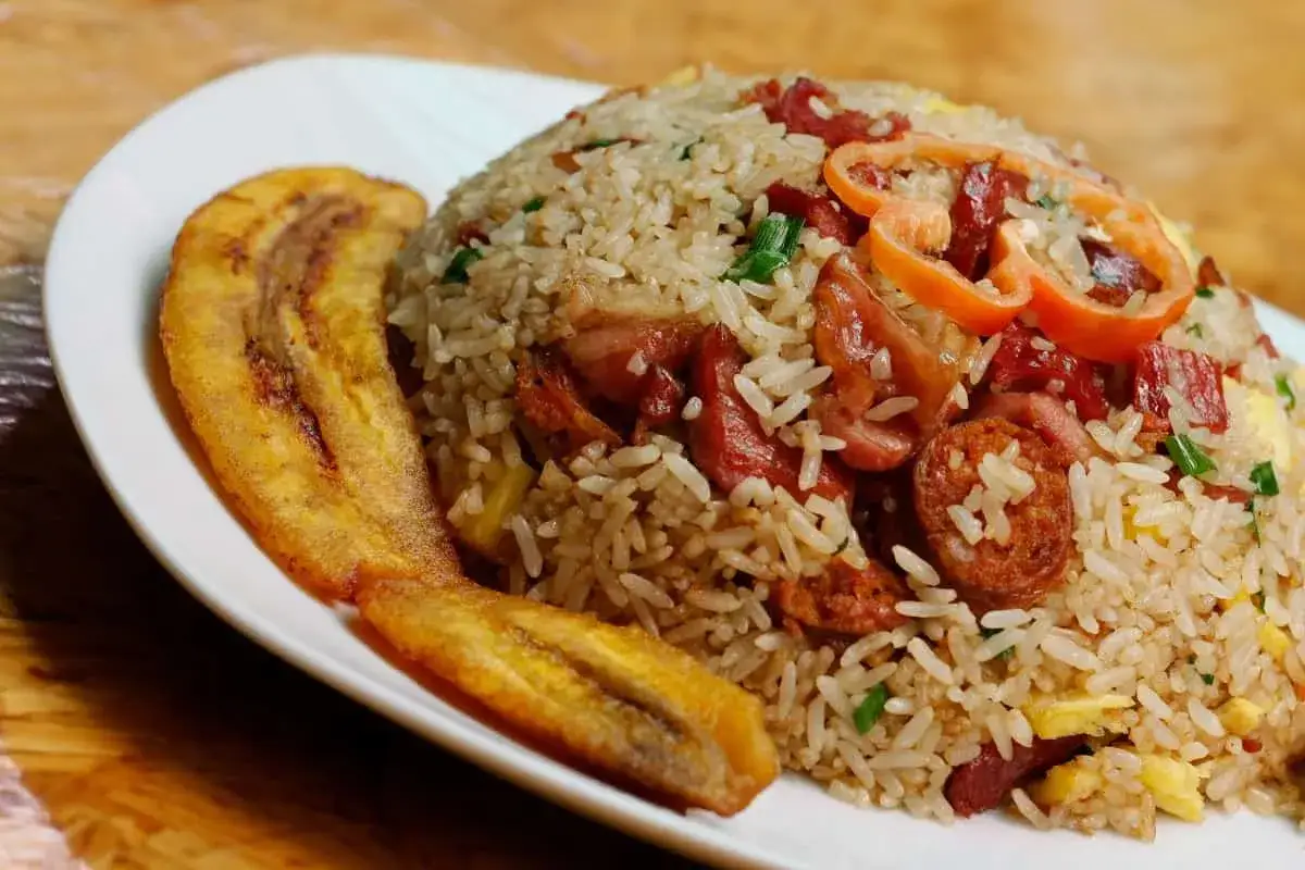 Un plato de arroz a lo pobre con plátano frito, salchicha y huevo.