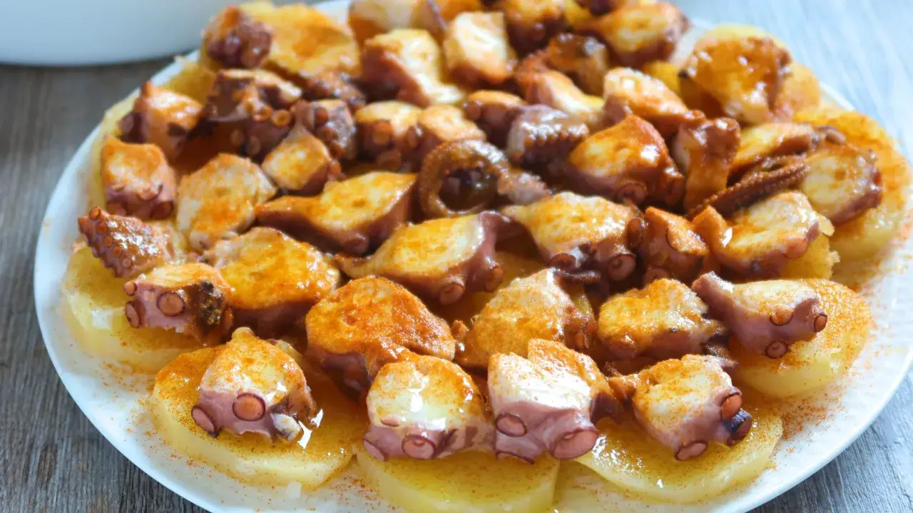 Pulpo a la gallega servido sobre patatas cocidas, espolvoreado con piment&oacute;n y aceite de oliva.