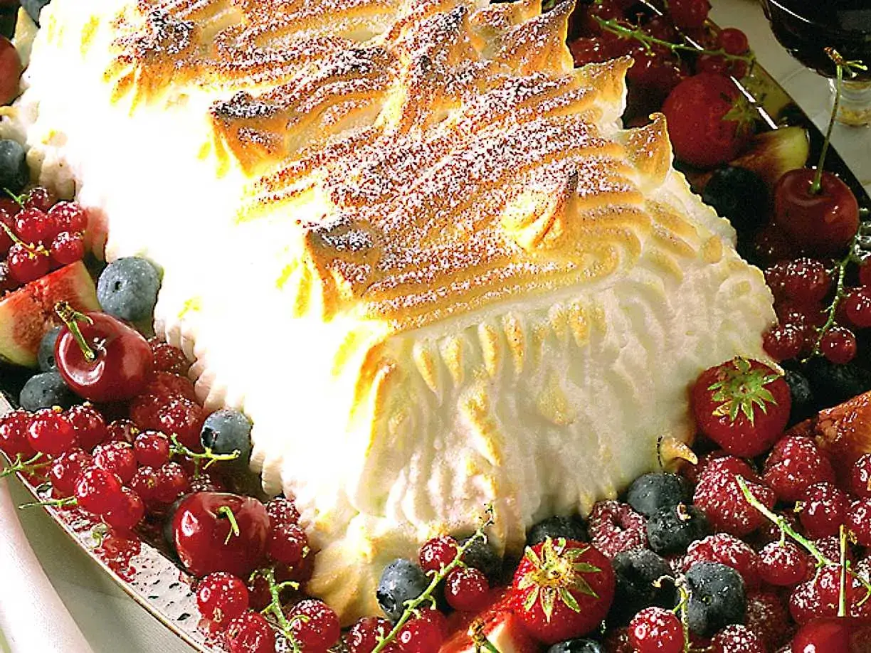 En vacker glace au four, täckt av maräng och omgiven av färska bär.