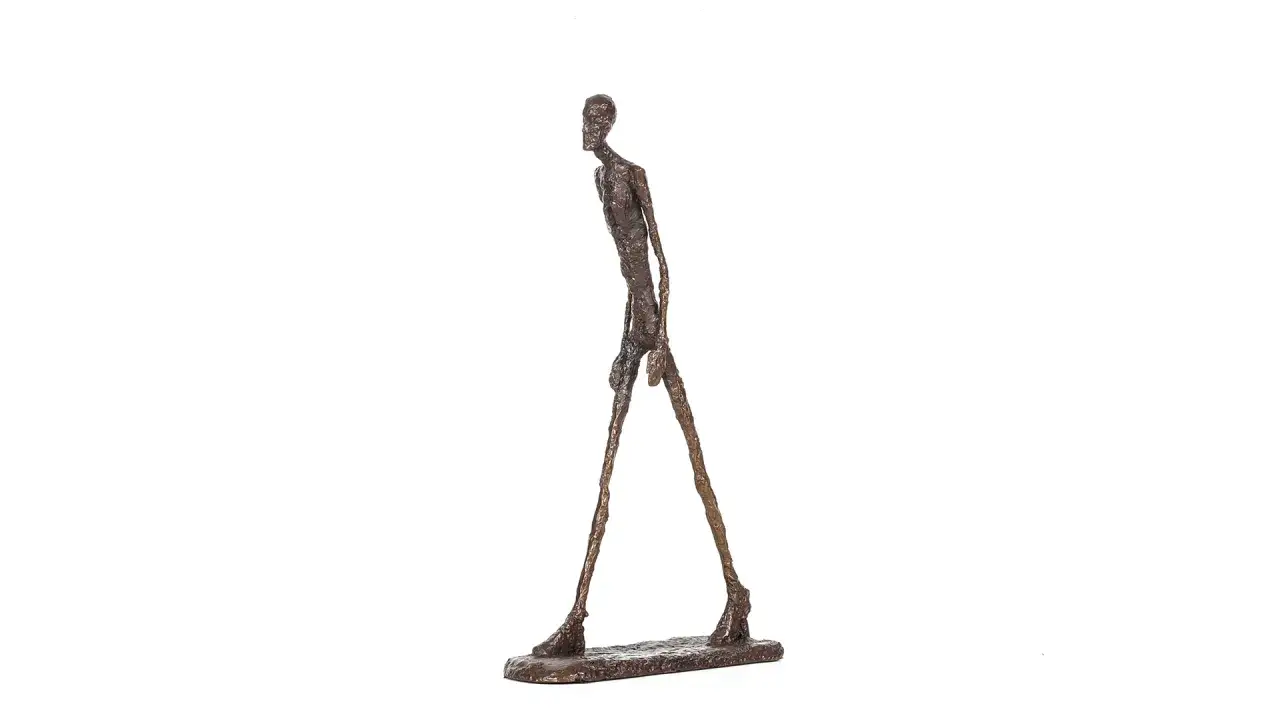 Sculpture d'un homme qui marche, mince et &eacute;lanc&eacute;, en bronze patin&eacute;, sur un socle rectangulaire.