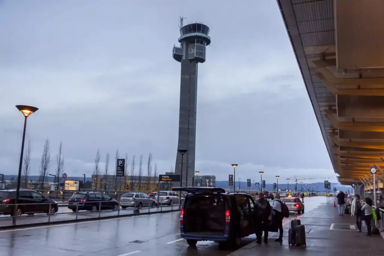 Wieża kontrolna na oslo lotniska. Samochody i ludzie przy terminalu, deszczowa pogoda.